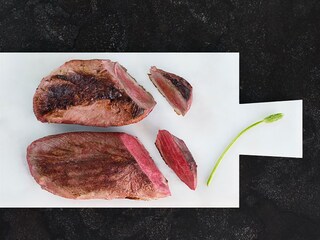 Immagine comparativa di due petti d'anatra arrosto. Quello cotto con il metodo sotto vuoto ha mantenuto la forma originaria e ha preso un bel colore dorato, mentre la consistenza della carne è rimasta succulenta. Il petto d'anatra arrostito in un forno tradizionale, invece, si è ristretto e la carne è dura.